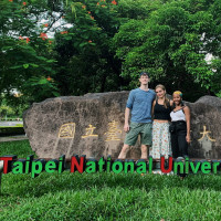 Students standing in front of the sign for Taipei National University of the Arts