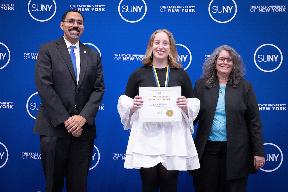 SUNY Chancellor John D. King, Sara Richter '24 holding award certificate, Purchase President Milagros Peña.