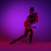 Raven Barkley '15 / Photo: Todd Rosenberg, Courtesy Charlotte Ballet (Barkley holds a dance pose bathed in purple light.)
