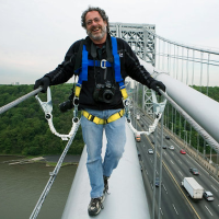 David Handschuh stands on a bridge with belt straps attached to the railings