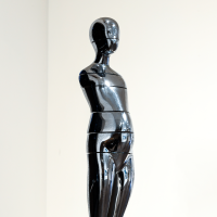 Silver metallic sculpture on a base with a white background