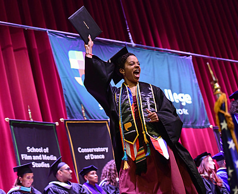 Student holds up diploma on stage