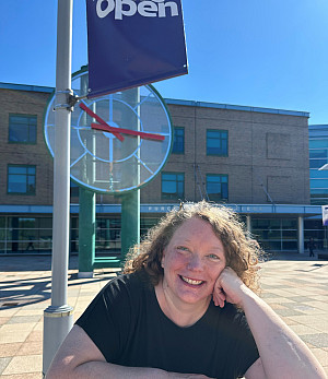 Tracey is smiling in front of the clock tower and the Student Services building. She is wearing a black shirt and has strawberry blonde, ...