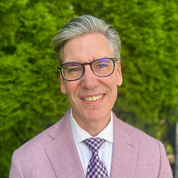 Michael Steiper in pink blazer, white shirt, and heliotrope and puce pattern tie