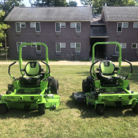 2 Greenworks electric riding mowers on a small patch of grass in Alumni Village