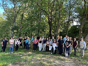 A group of students standing in a shaded area on the outskirts of a forest