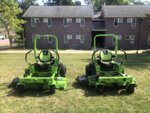 2 Greenworks electric riding mowers on a small patch of grass in Alumni Village
