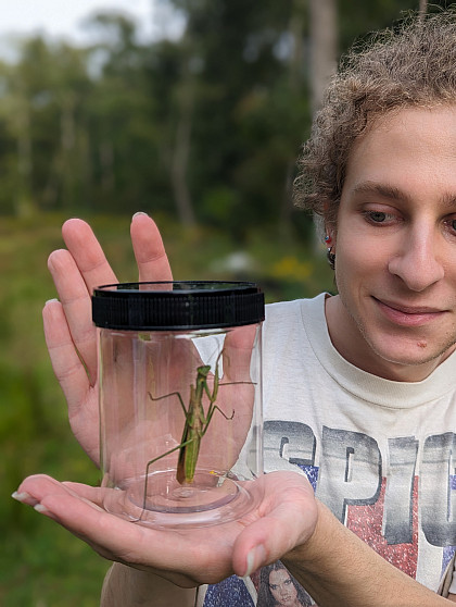 Student holds a container with a grasshopper.