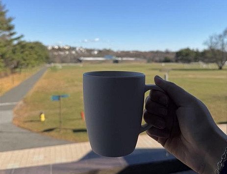 Holding a reusable mug with Great Lawn in background