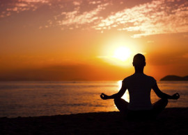 person meditating with sunset