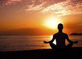 person meditating with sunset