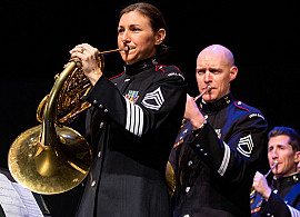 Four musicians in army uniforms playing french horns