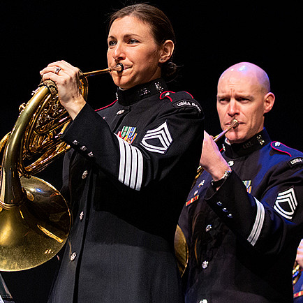 Four musicians in army uniforms playing french horns