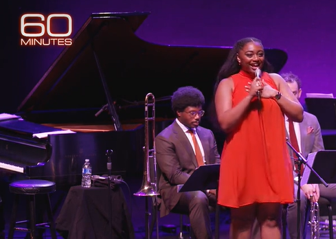 60 Minutes on the upper left corner of an image of Samara Joy performing on the Purchase College Performing Arts Center stage with her band