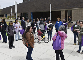 A group of alumni gathered around a student tour guide as they make their way through campus on a walking tour