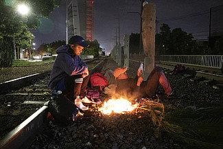 A group of Honduran men make campfire along the railroad tracks in Guadalajara