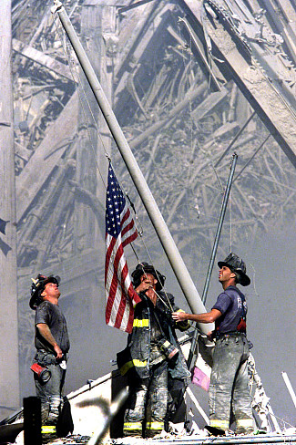 NEW YORK CITY, NY 09/11/01 SEPT. 11TH / TERRORIST ATTACKS ON WTC: 3 FDNY firemen raise an American flag amidst the rubble of the World Tr...