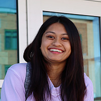 Smiling woman in a pink sweatshirt and long dark hair