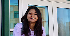 Smiling woman in a pink sweatshirt and long dark hair