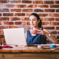 Young businesswoman working on laptop and drinking coffee