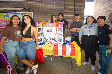 A group of people smiling around a table outside of a building.