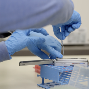 hands in blue rubber gloves using a benchtop data sequencer