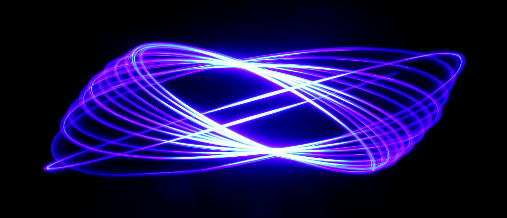 A long exposure of a hanging blue LED light as it swings and spins, creating an ovular warp patte...