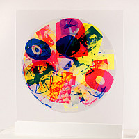 A colorfully printed round pexiglass wheel on a stand