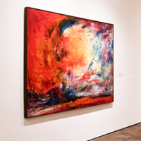 A modern art gallery with brightly colored abstract paintings on white walls, spotlights above, and two white sculptures displayed on black