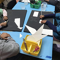 Close up of the hands of three young students creating art projects