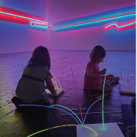 Several young children create glow sculptures in the Proscenium gallery.