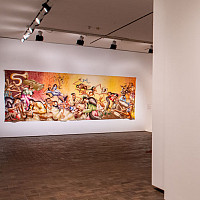 White gallery wall with exhibition title in red type and a brightly colored mural in the background