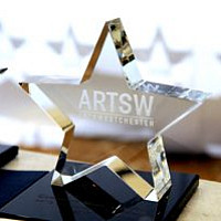 The ArtsWestchester Annual Arts Award is a glass star with the ArtsW logo sitting on a glossy base
