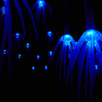 A sea of glowing blue shapes with tentacles float within a dark background