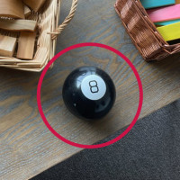 Magic 8 Ball with a red circle on a table with baskets of wooden blocks