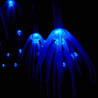 A sea of glowing blue shapes with tentacles float within a dark background