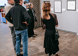 Adults in a gallery looking at drawings