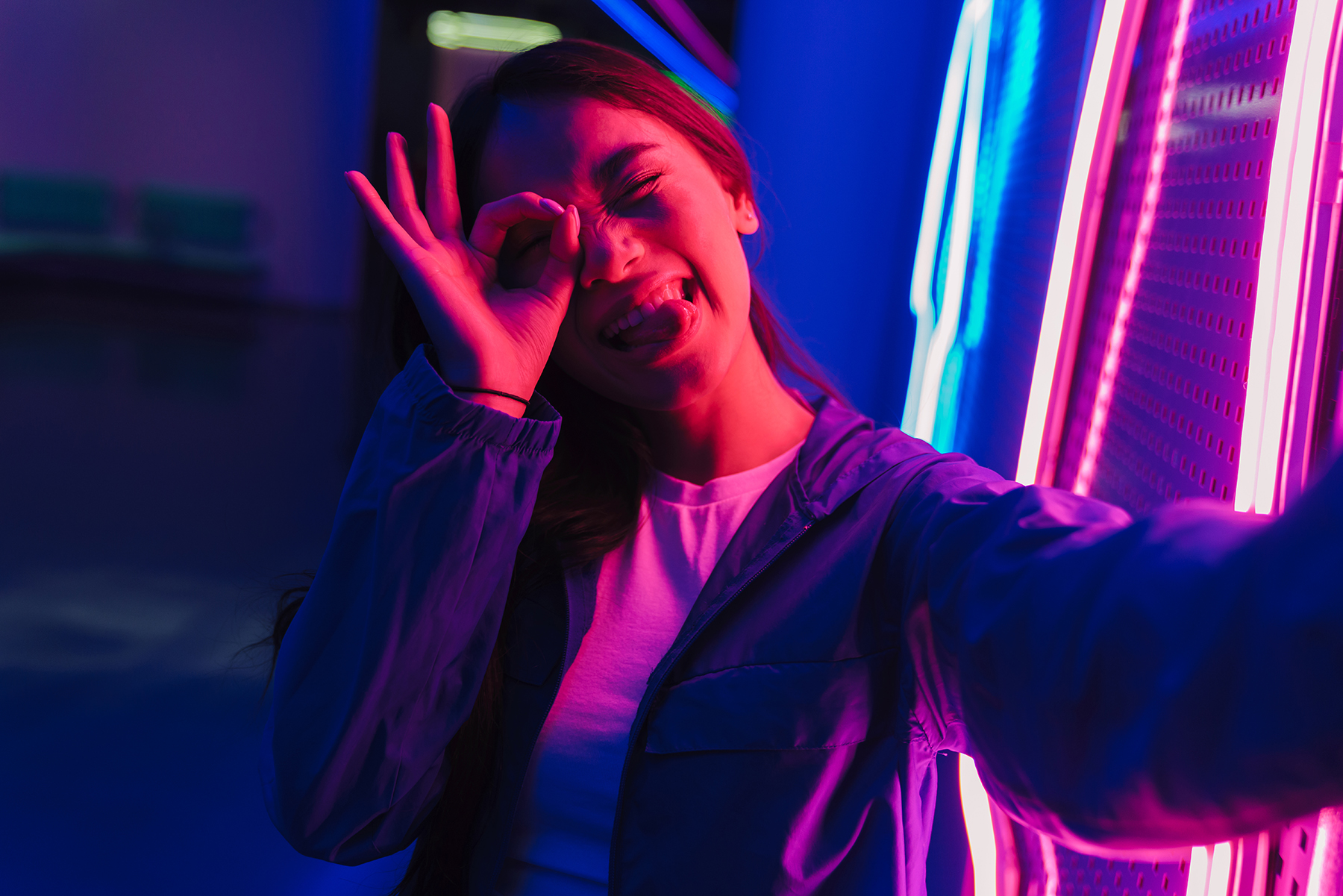 Young asian woman with long dark hair standing in front of a neon wallOc