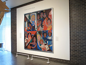Oversize 8' square multi-color oil painting of Black women on a brown brick museum wall