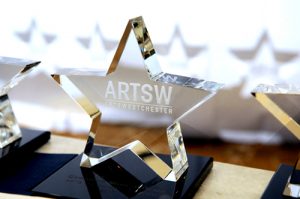 The ArtsWestchester Annual Arts Award is a glass star with the ArtsW logo sitting on a glossy base