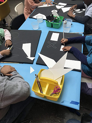 Close up of the hands of three young students creating art projects