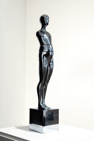 Silver metallic sculpture on a base with a white background
