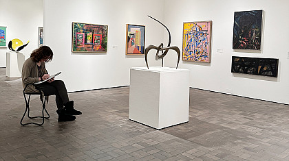 Image of a college-age student seated on a stool with a sketchpad drawing works from the Museum's collection