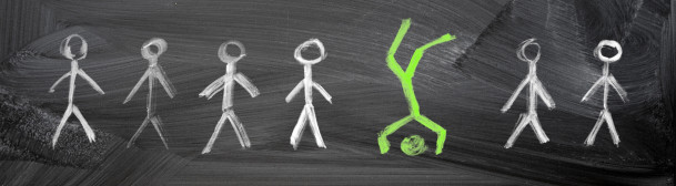 Chalkboard with green chalk figure standing on head in a crowd of identical white chalk figures