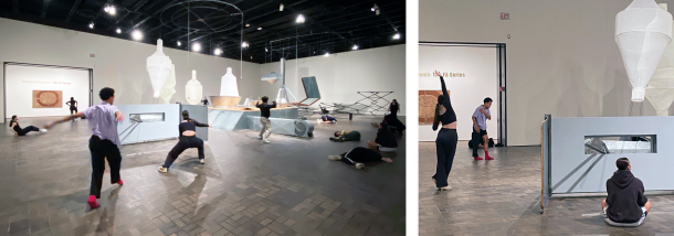 Dance students in various poses and movement in a museum gallery with pieces of a large industrial sculpture in the background