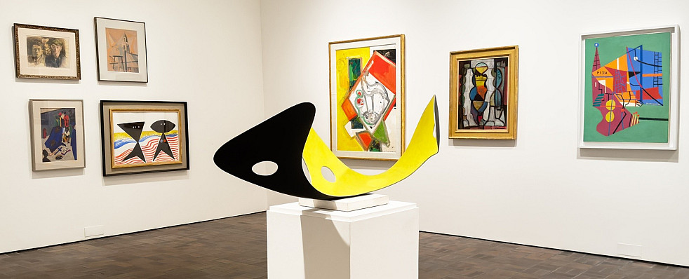 Photo of art on the Museum walls and a large yellow sculpture in the foreground