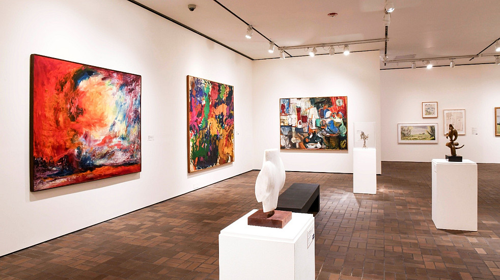 Photo of art on the Museum walls with two small sculptures on pedastals