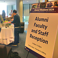 welcome sign in foreground, attendees at food table in background