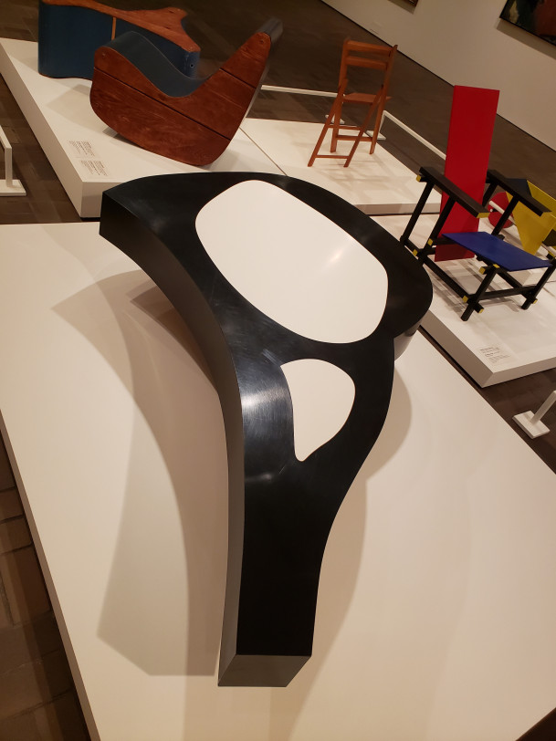 A black-and-white cocktail table in the shape of a lamb chop. The table is mostly black with the white parts only on top being where the ...