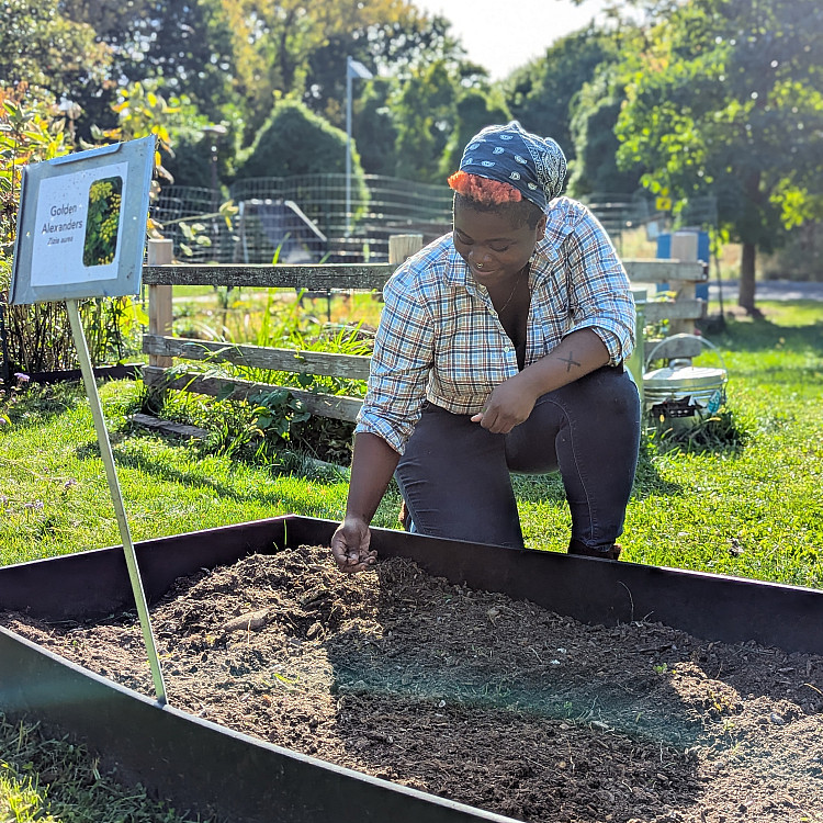 Land stewardship and invasive species intern handling compost in the on-campus Purchase College garden.